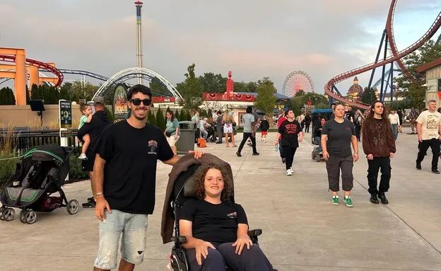 שחף עומד מאחורי אמור בכיסא הגלגלים בפארק שעשועים לקראת ערב